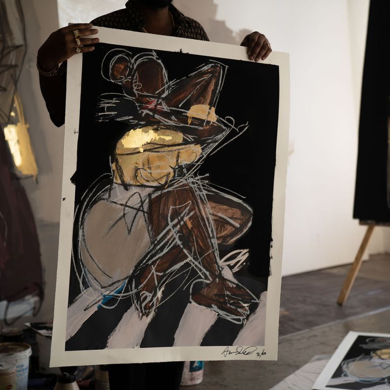 artist holding up his large print in front of his body in his studio