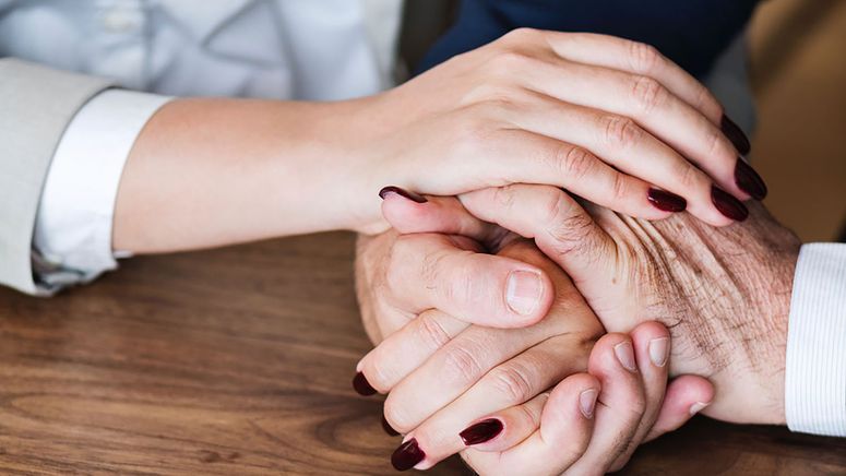 Palliative care- close up photo of young female hands holding and older person's hands