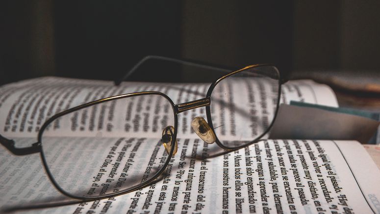 Close up photo of glasses sitting on a book someone is reading while receiving in home care