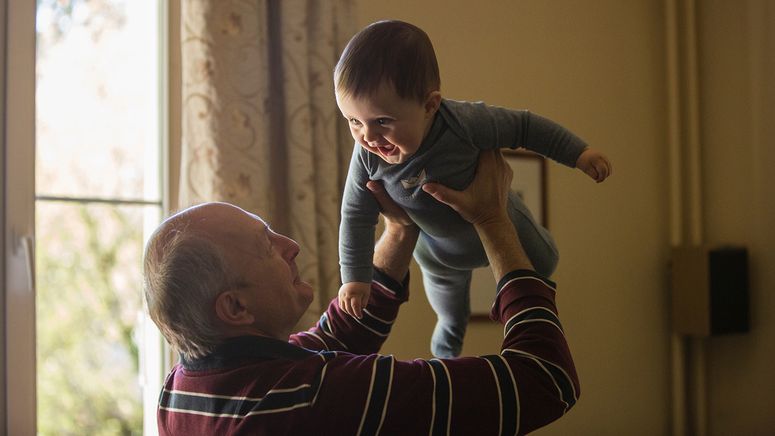 Residential aged care visitors- photo of an older man holding a smiling baby up above his head