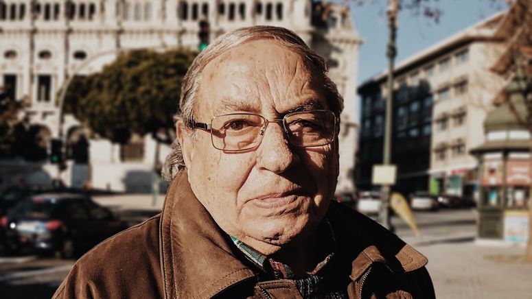 Dementia in the family- Photo of an older man posing on the street in front of a building, wearing a brown jacket and glasses