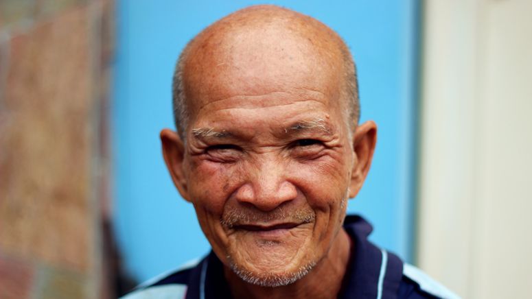 Photo of a balding older asian man smiling at the camera
