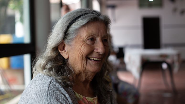 Types of respite- Photo of an older lady with grey shoulder length hair and black head band smiling.