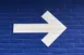 A white arrow pointing right painted on a blue brick wall