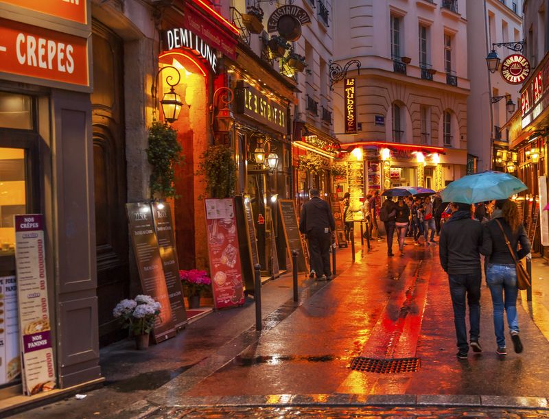 Wine bars and restaurants on a street in the Latin Quarter on a rainy evening