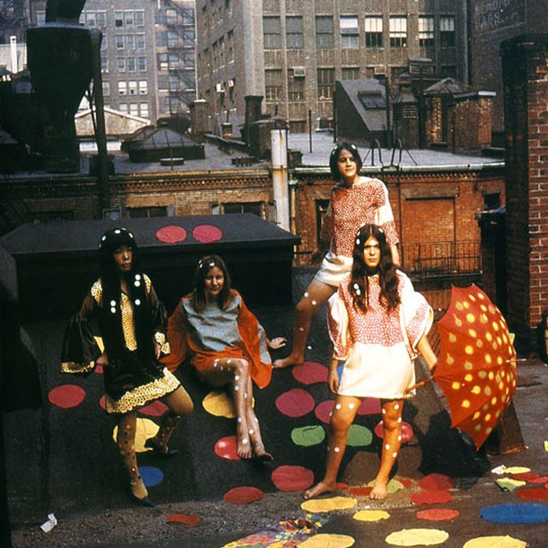 Yayoi Kusama and three others on a New York rooftop, wearing colourful polka-dot outfits, surrounded by large polkadots placed on the floor and walls