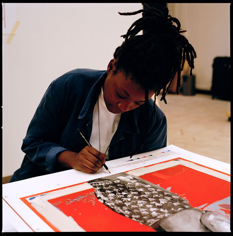 Artist signing a print using a pencil