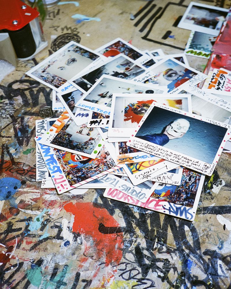 stack of polariod images on graffiti-covered desk