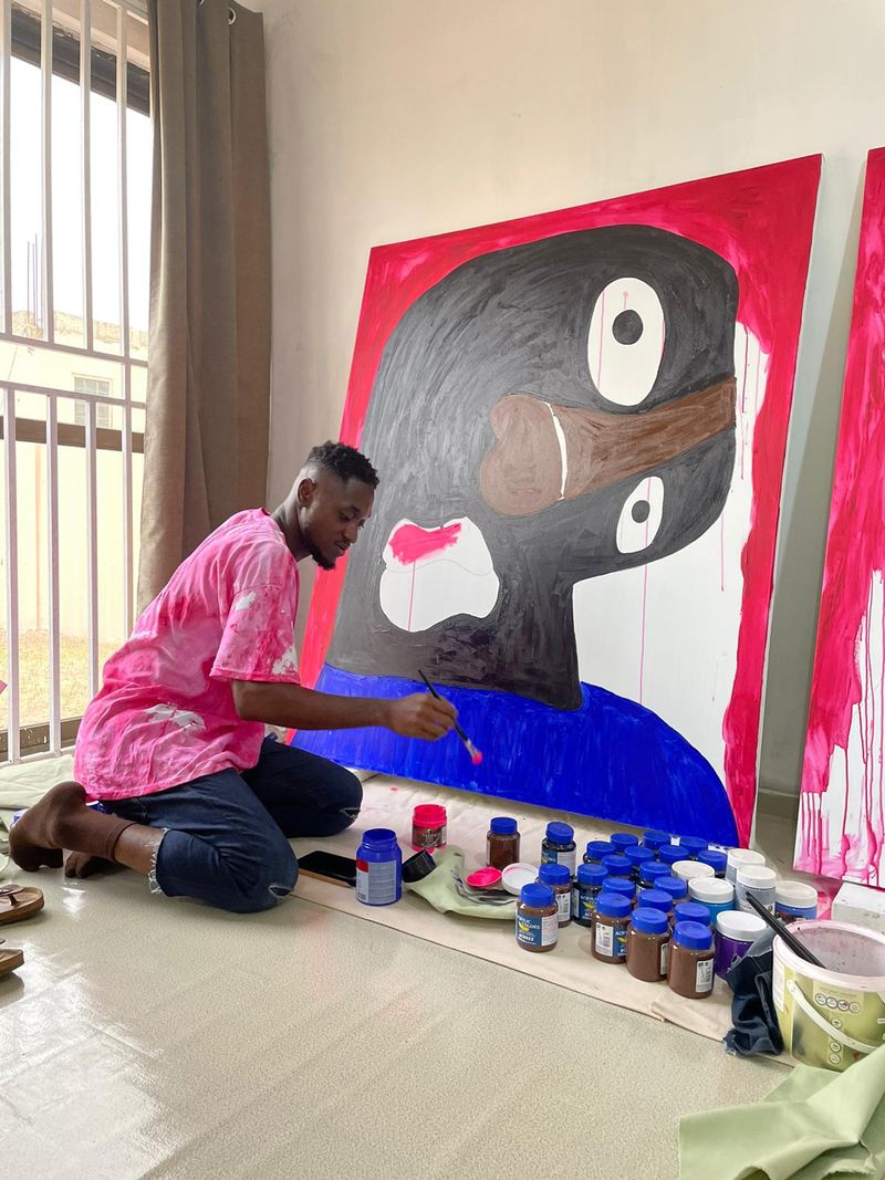 Isshaq Ismail kneeling in his studio working on a large painting