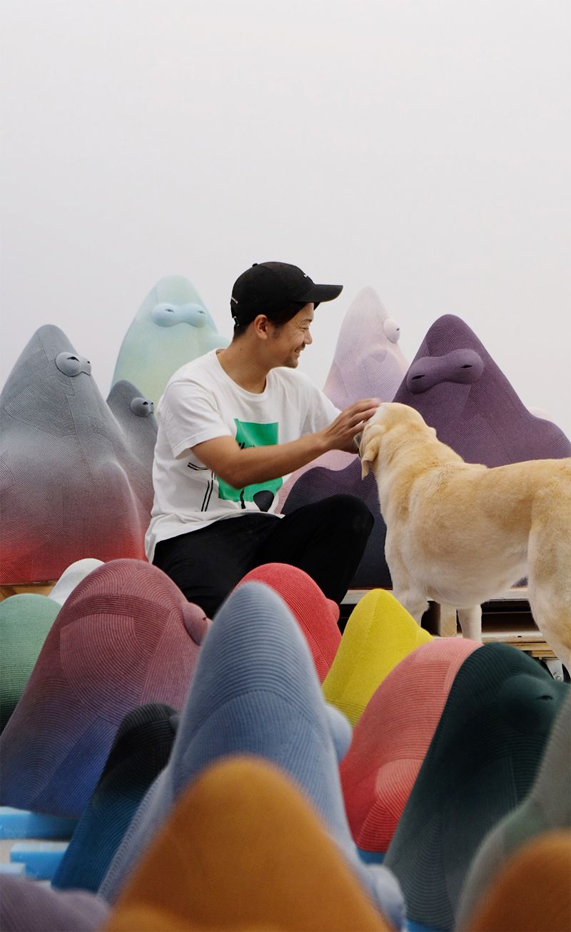 En Iwamura surrounded by colourful ceramic sculptures with his dog