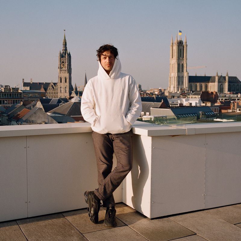 David Rudnick wearing a white hoodie on the rooftop of his Ghent studio
