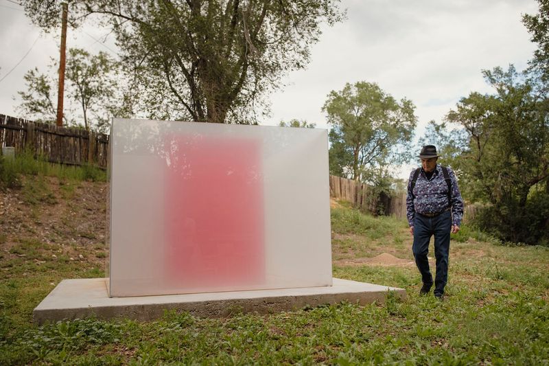 Larry Bell walking outdoors next to a white and pink glass box