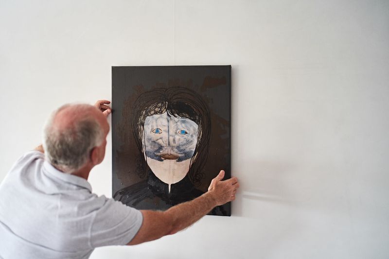 A man hanging an artwork on a wall, Michael Kinsbergen