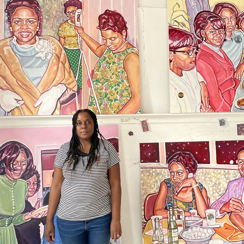 Esiri Erheriene-Essi in front of four vibrant paintings in her studio