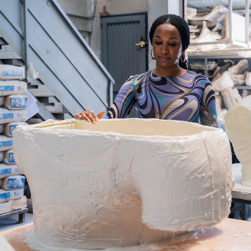 Tschabalala Self inspecting a large plaster cast element for her public sculpture