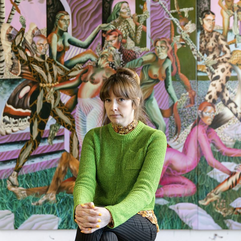 Jessie Makinson in a green jumper, seated in front of a large painting in her London studio