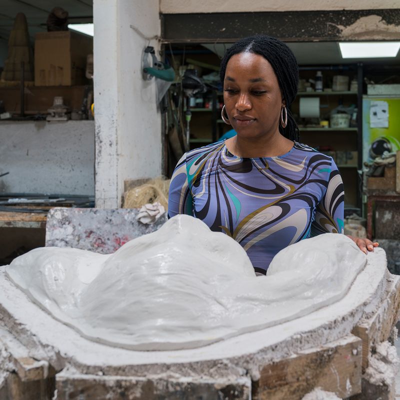 Tschabalala Self inspecting a plaster cast of the face for her largest sculpture to date