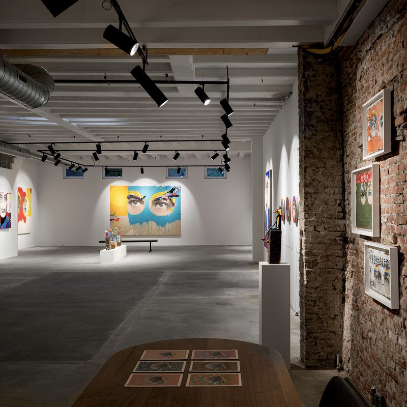 exhibition space with exposed brickwor, spotlights and a large wooden table