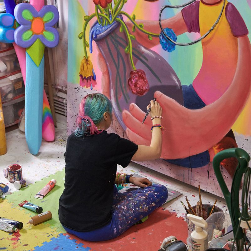 Super Future Kid sitting on a colourful foam matt, finishing a painting