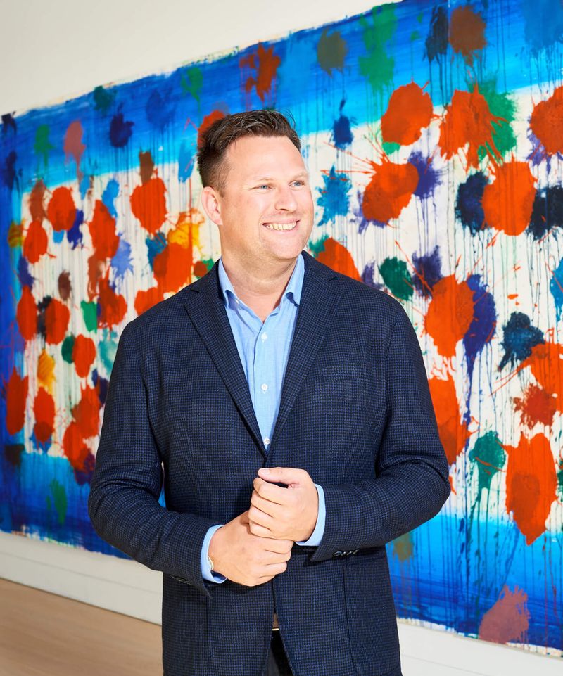 Portrait of Matt Langton from Phillips auction house standing and smiling against a painting