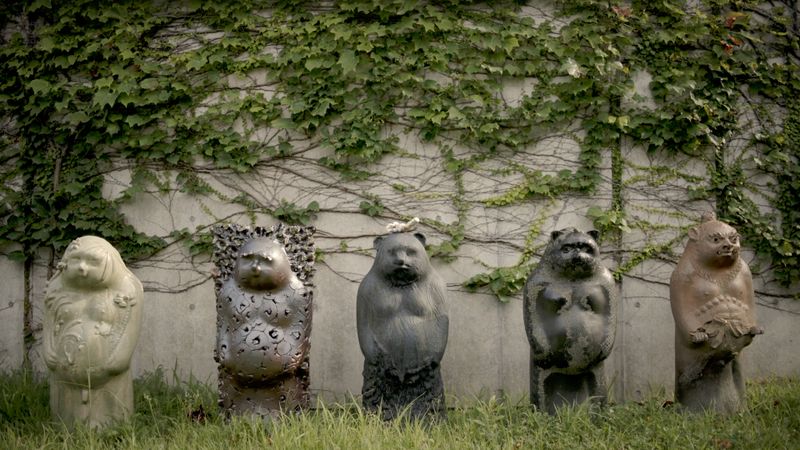 five sculptures of tanuki lined up outside