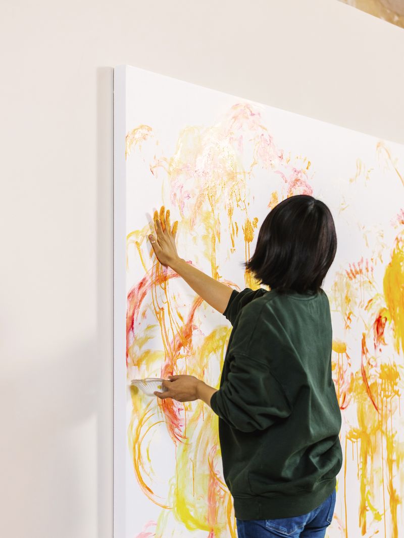 Ayako starting a big painting with broad strokes in orange, red and yellow