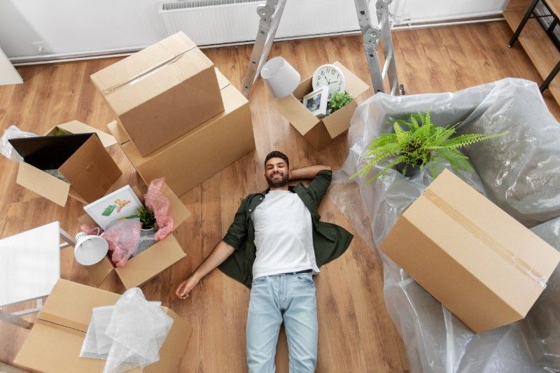 Muž ležící na podlaze při stěhování papírových krabic