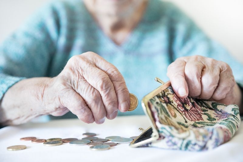 Seniorka dává mince do peněženky