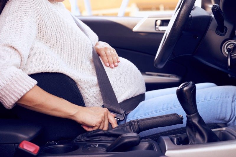 Připoutaná těhotná žena za volantem