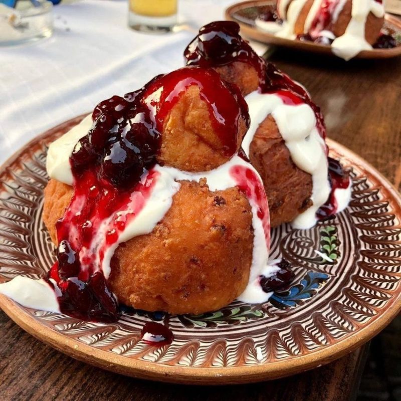 Papanasi, Romanian cheese donuts, served with fruit compote and sour cream