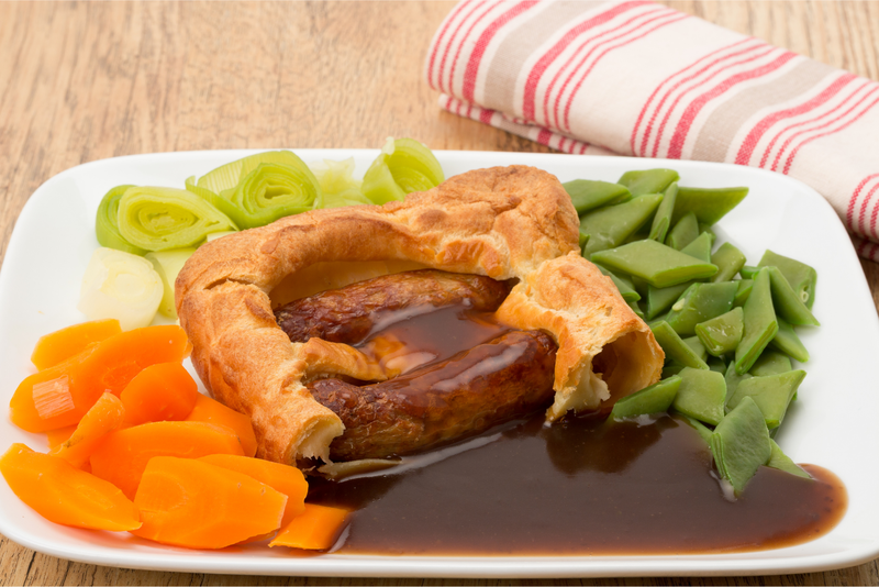 Classic British dinner of Toad in the Hole with vegetables and thick gravy