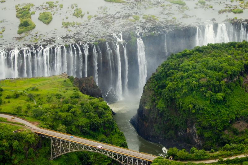 An aerial view of the immense Victoria Falls with a bridge in the foreground