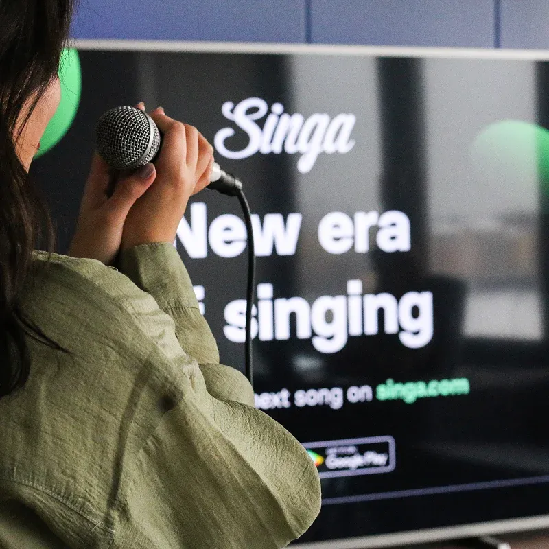 Woman in headphones beside Singa New era of singing tagline, square hero of the Singa karaoke case study