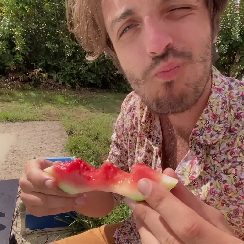Man eating watermelon outdoors in a TikTok video still