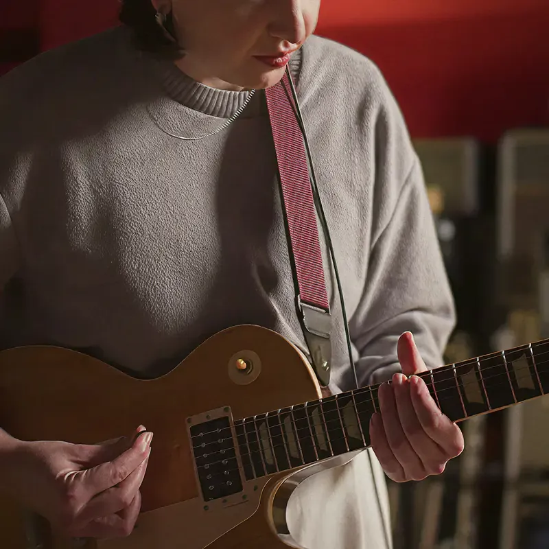 Musician playing a guitar with a red strap, from the Sound of Leffe campaign