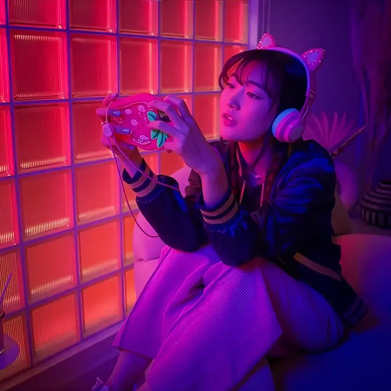 Woman in cat-ear headphones playing a handheld game in a neon-lit room, from the MassiveMusic TikTok campaign