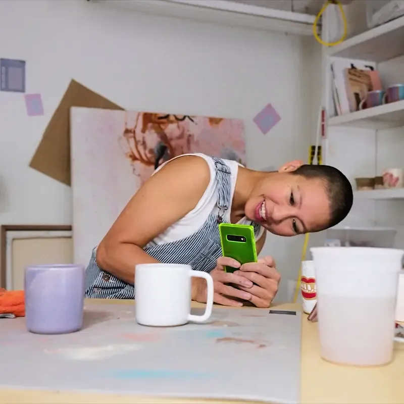 Artist filming herself on a phone in a creative studio space, from the MassiveMusic TikTok campaign