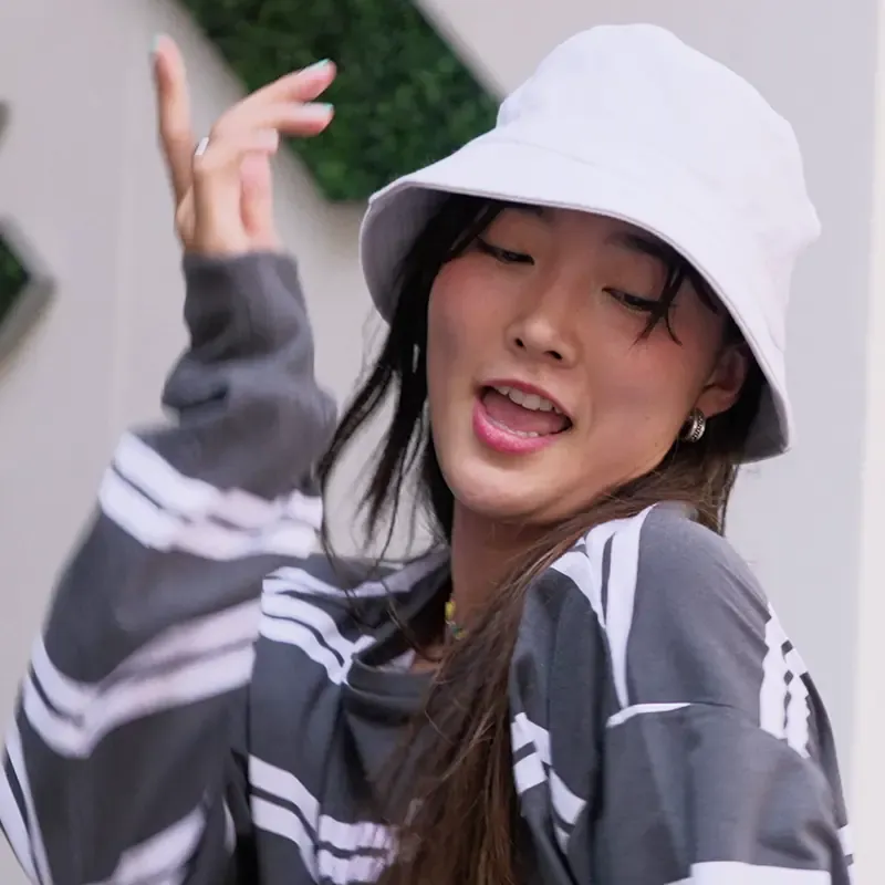 Woman in a white bucket hat dancing outdoors, from the MassiveMusic TikTok campaign