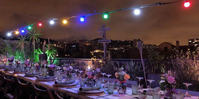 Long table on a rooftop terrace in Barcelona with lights hanging above it
