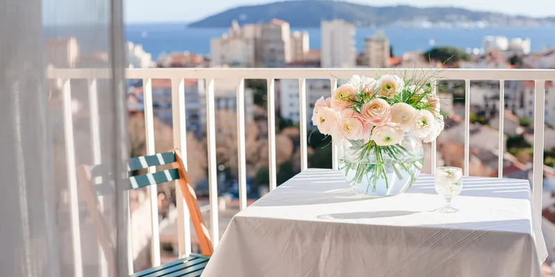 Balcony with table and flowers in glass vase overlooking ocean