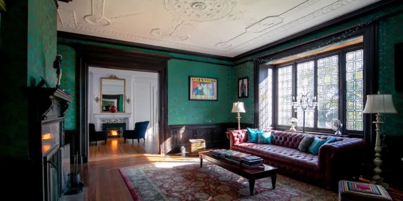 Historic house in New Rochelle with green walls, wooden floors , carpet and burgundy couch