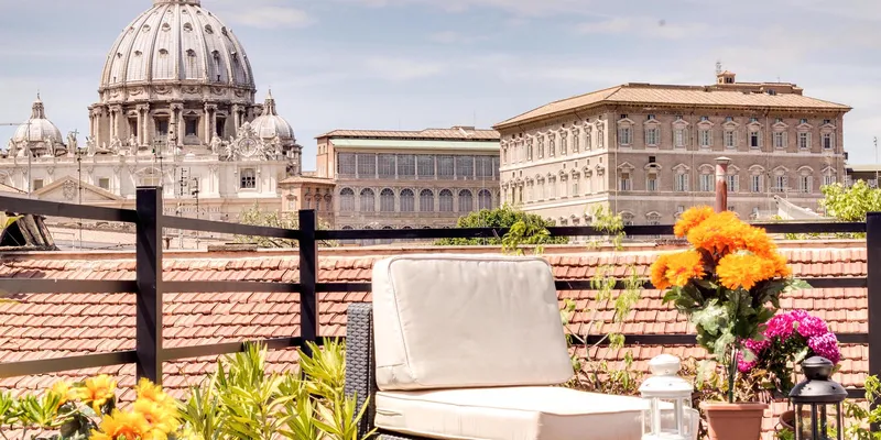 Terrace with chair and table with flowers on it with St. Peter's Basilica in the background