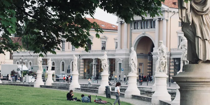 Prato della Valle in Padova with statues and people sitting on grass