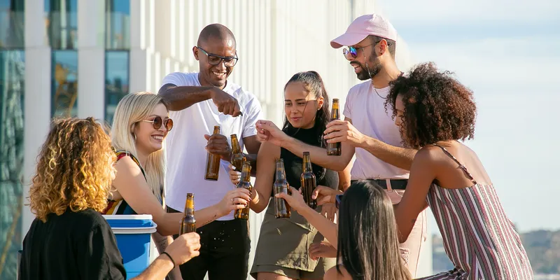People standing together and holding glass bottles on a rooftop