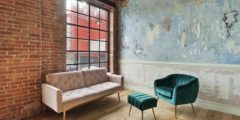 Brick studio in Brooklyn with pink couch and green chair with footrest