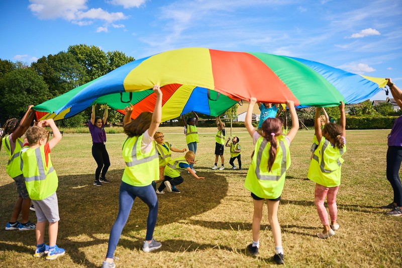 JAG staff and children playing parachute games on a field