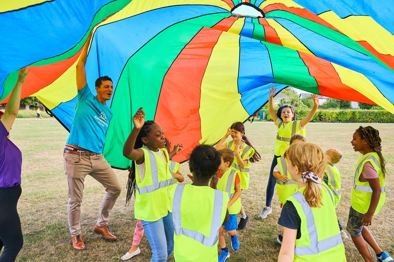 JAG staff and children playing parachute games on a field
