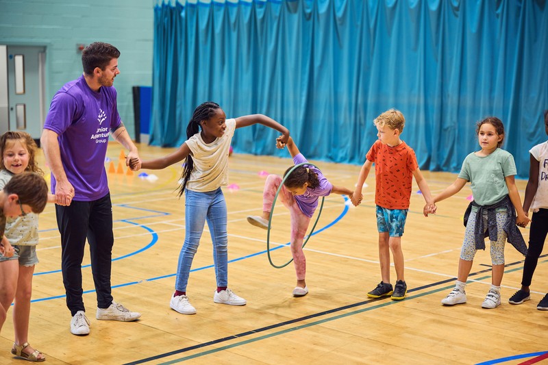 JAG staff and children playing with a hula hoop in sports hall