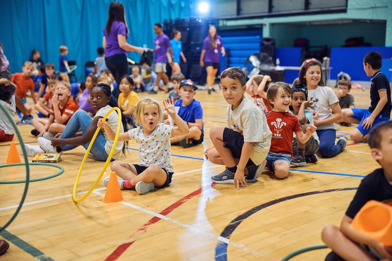 Children sat down excited in a sports hall
