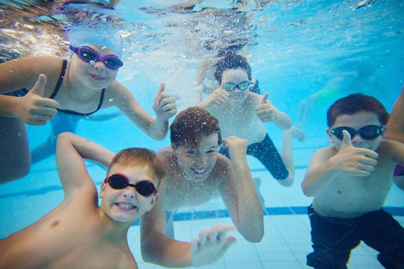 Group photo of children smiling under water in a swimming pool